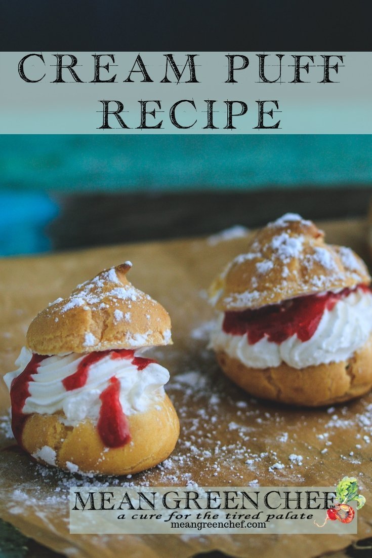 Cream Puffs with Strawberry Coulis shown with a sprinkling of powdered sugar on an old blue wooden background