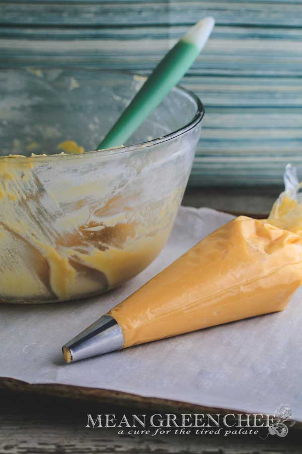 Pate a Choux Pastry in a piping bag with mixing bowl in the background.