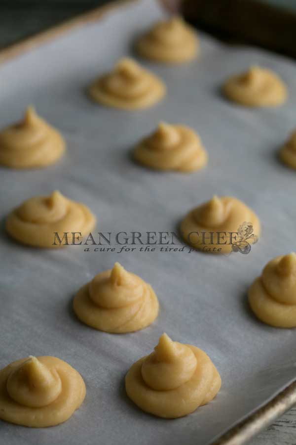 Pate a Choux Pastry piped onto a baking sheet lined with parchment paper.