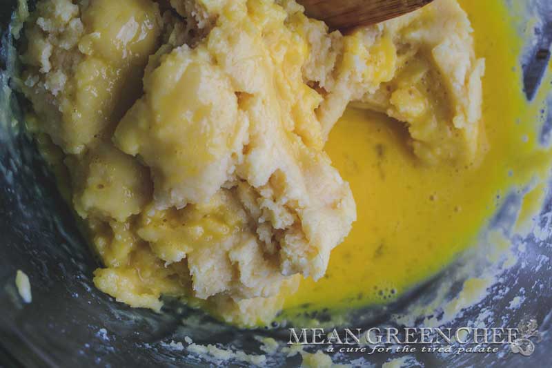 Pate a Choux Pastry off the stove with egg yolks being combined into the dough.