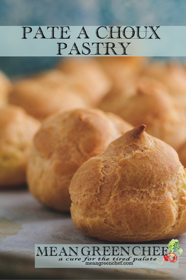 Pate a Choux Pastry baked to a golden brown sitting on a sheet pan lined with parchment paper.