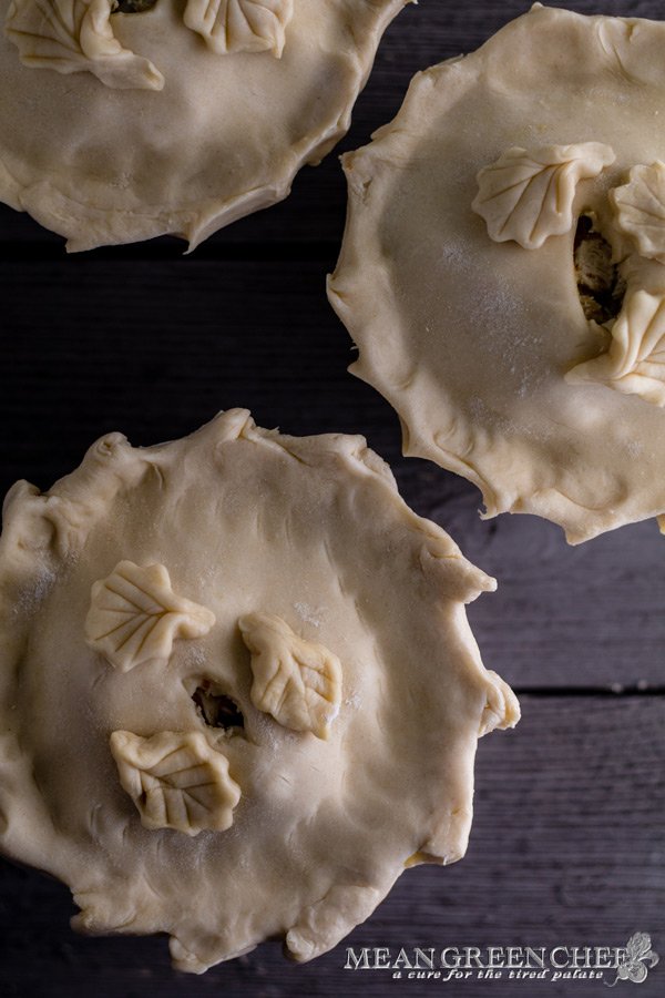 Overhead photo of three large double crust chicken pot pies in white ramekins on a gray wooden background. Mean Green Chef