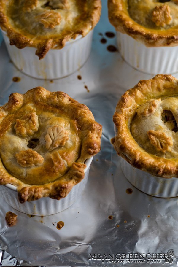Overhead photo of four large double crust chicken pot pies in white ramekins on a baking sheet lined with foil. Mean Green Chef