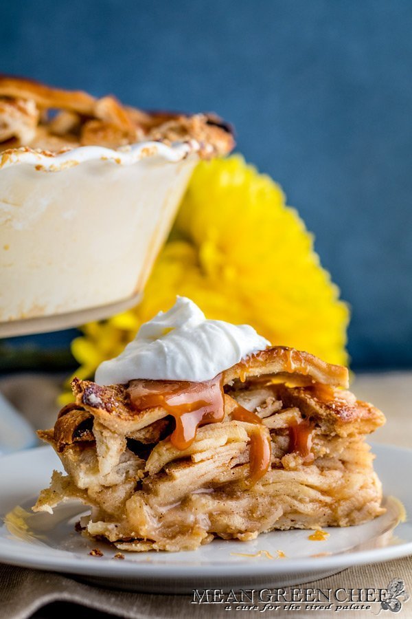 Slice of Caramel Apple Pie garnished with whipped cream and dripping in caramel
