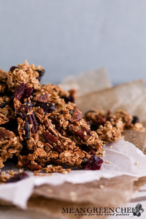Side photo of a pile of Brown Butter Granola sitting on wrinkled parchment paper. Mean Green Chef