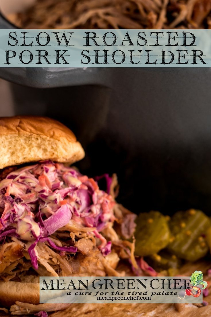 Side photo of Slow Roasted Pork Shoulder used on a pulled pork sandwich with red cabbage slaw and pickles off in the background. Mean Green Chef