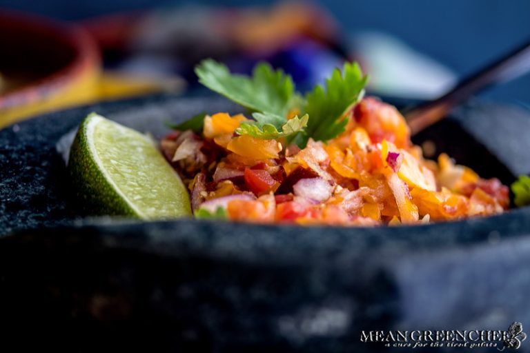Mortar and pestle filled with fresh tomato salsa garnished with cilantro and fresh lime.