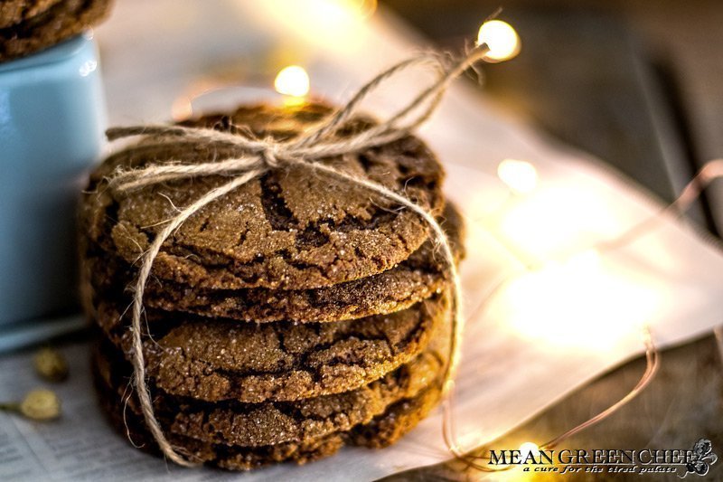 Stack of Molasses Cookies, tied with twine and sitting on newspaper that has been scattered with white flower buds. Mean Green Chef Best Ever Molasses Cookies