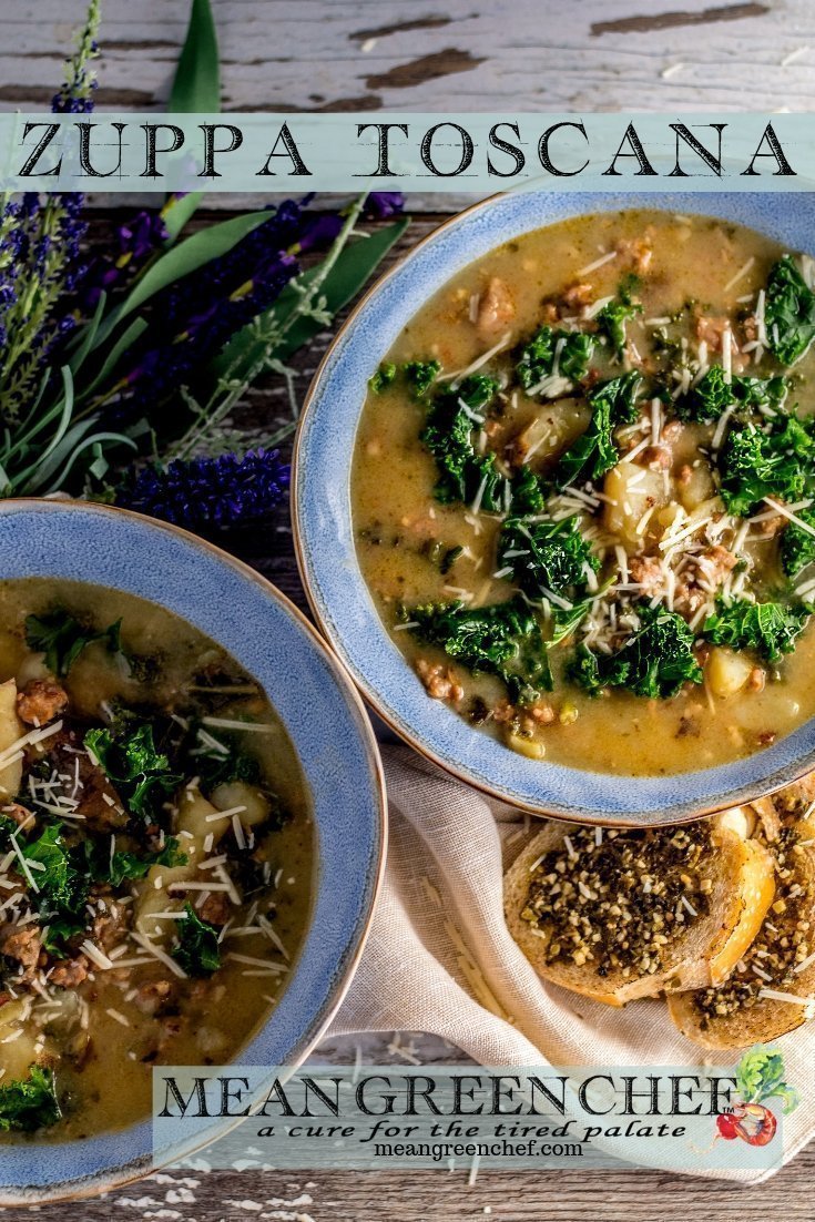 Overhead photo of Zuppa Toscana in two large blue bowls with rough edges. A small beige linen napkin and bread spread with pesto. Mean Green Chef