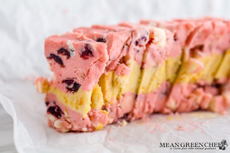 Photo of layered Orange Cranberry Icebox Cookie dough sliced on parchment paper.