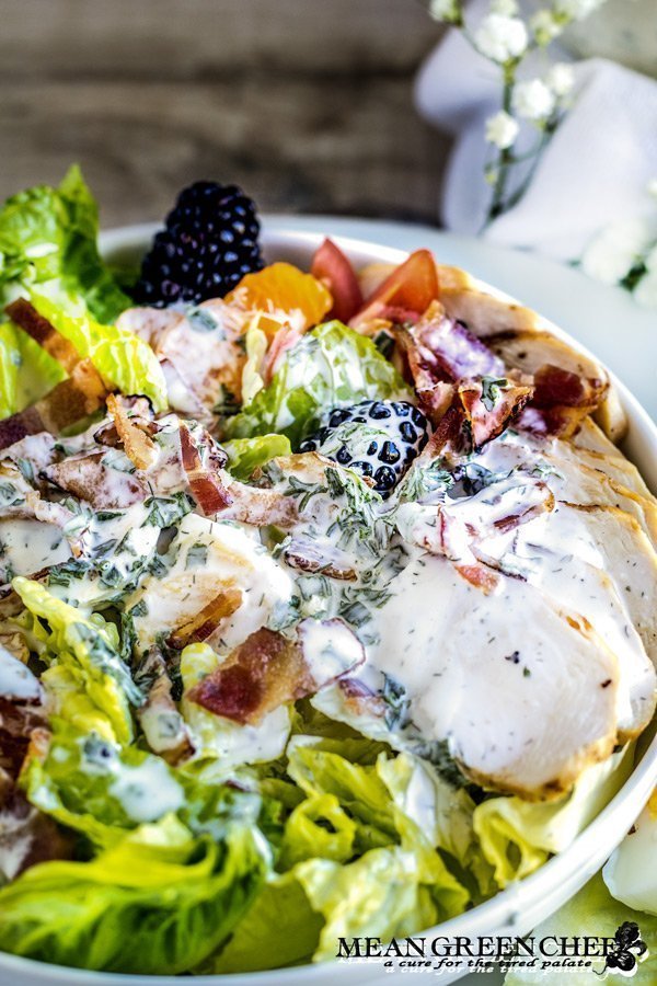 Herbed Buttermilk Ranch Dressing being poured over a chicken bacon ranch salad
