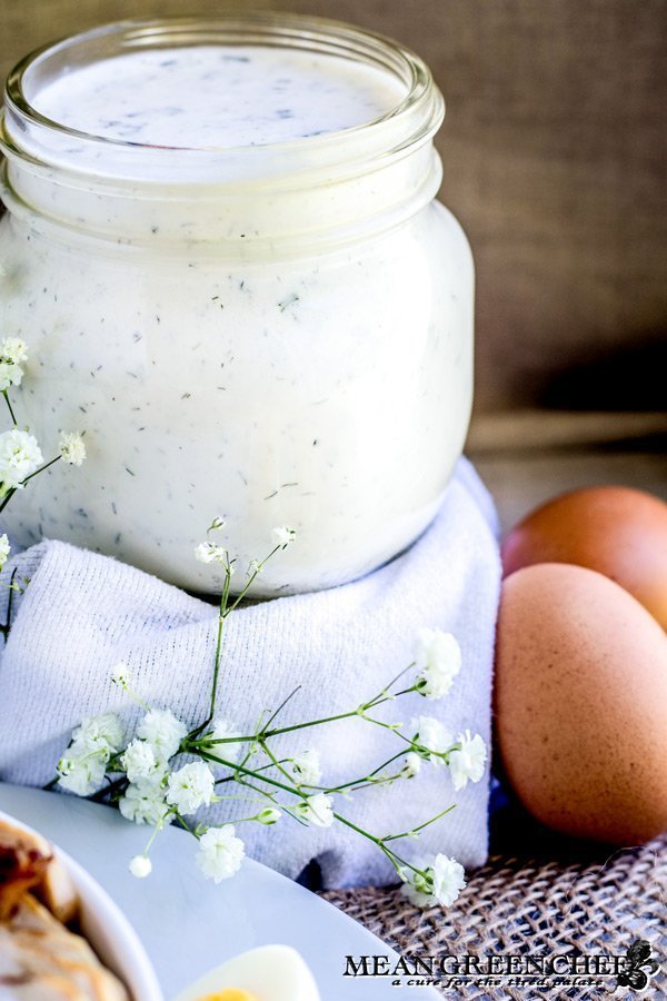 Herbed Buttermilk Ranch Dressing in a mason jar with chicken bacon ranch salad off to the side.